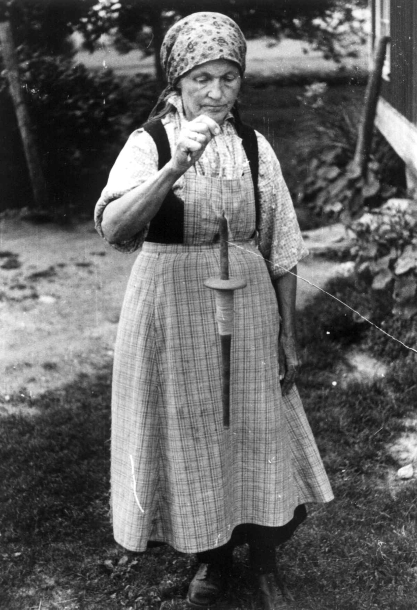 Anna Grostøl, Bø, Telemark 1940. Anne Østbø holder på med håndteinspinning.
