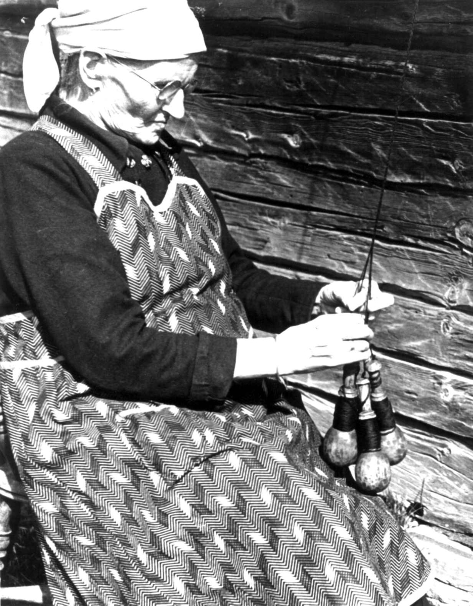 Anna Grostøl, Slingring. Anne Østby fletter garn ved hjelp av garnsneller. Røros, Sør-Trøndelag 1939.