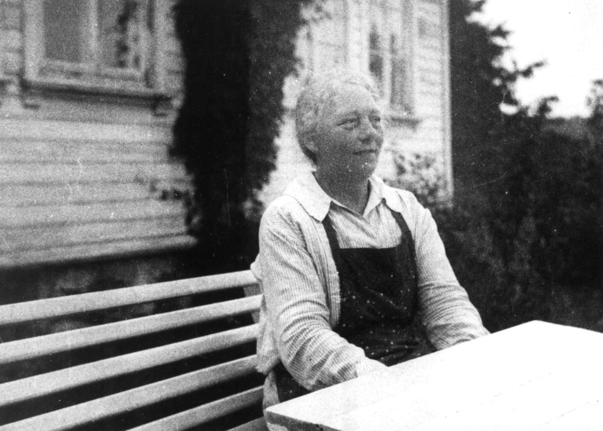 Anna Grostøl, Portrett av Sofuie Kjevik, født 1879. Hun sitter ved hagebordet med huset i bakgrunnen. Tveit, Kristiansand 1937.
