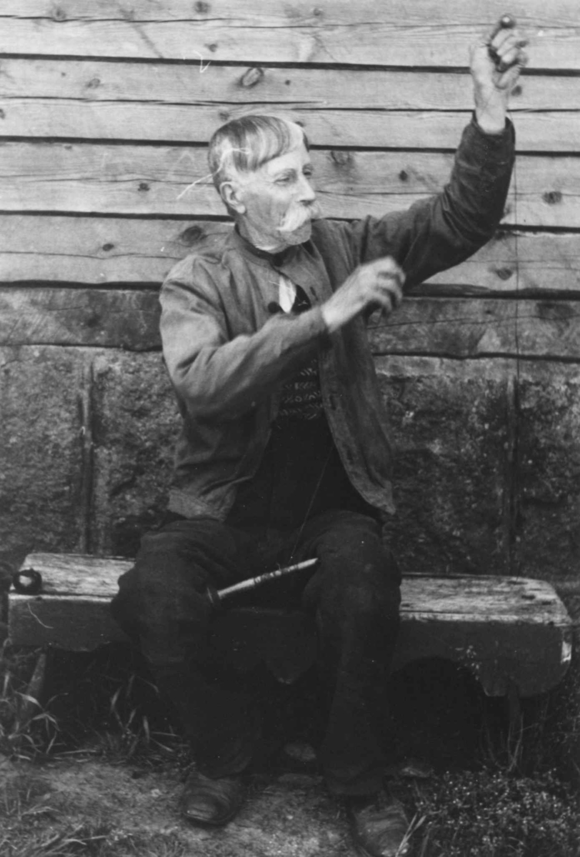 Anna Grostøl, En mann sitter med en håndtein og lager skomakertråd. Åseral, Vest-Agder 1943.