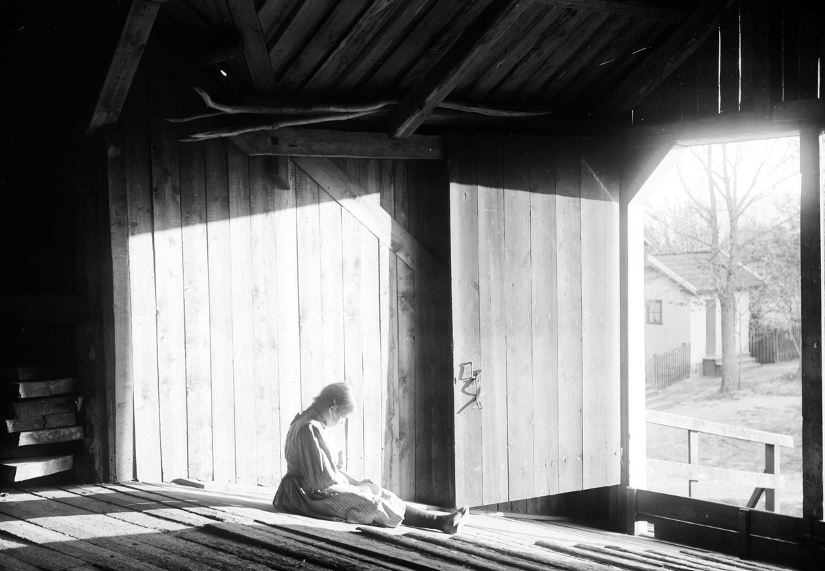 Juliane Fredrikke Langberg, Pike i kjole, Emily Holm, sittende på låvebrua, prestegården i Hurum. Hun er datter av sokneprest i Hurum 1897-1904, Olaf A. Holm, g. med fotografens søster Louise. Fra malerinne Juliane Fredrikke Langbergs (1856-1930) samling, tatt ca.1895-1910 med motivkrets slekt og venner samt steder tilknyttet…