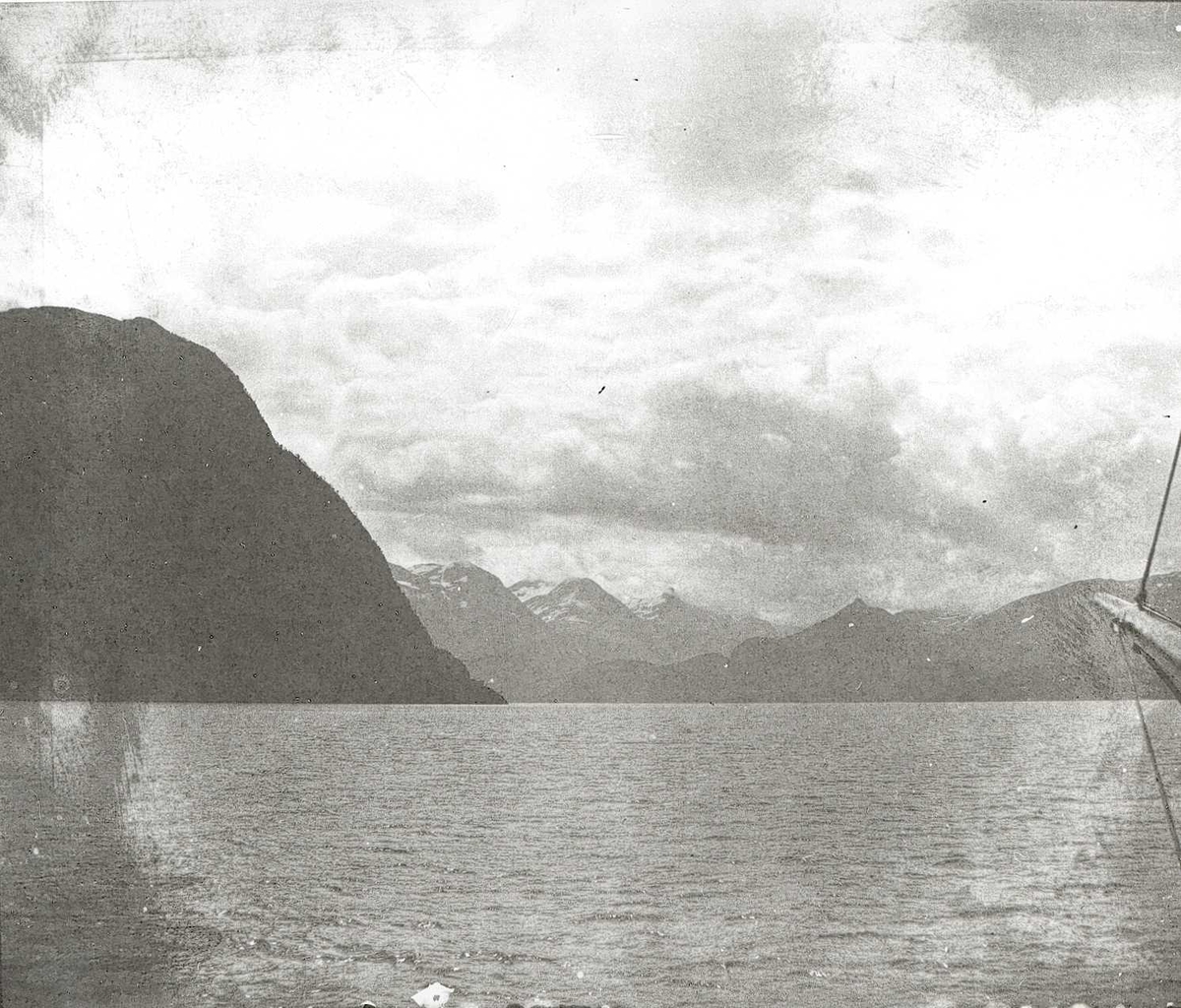 Tom Kent, Fjordlandskap med bratte fjell med snø på toppene.