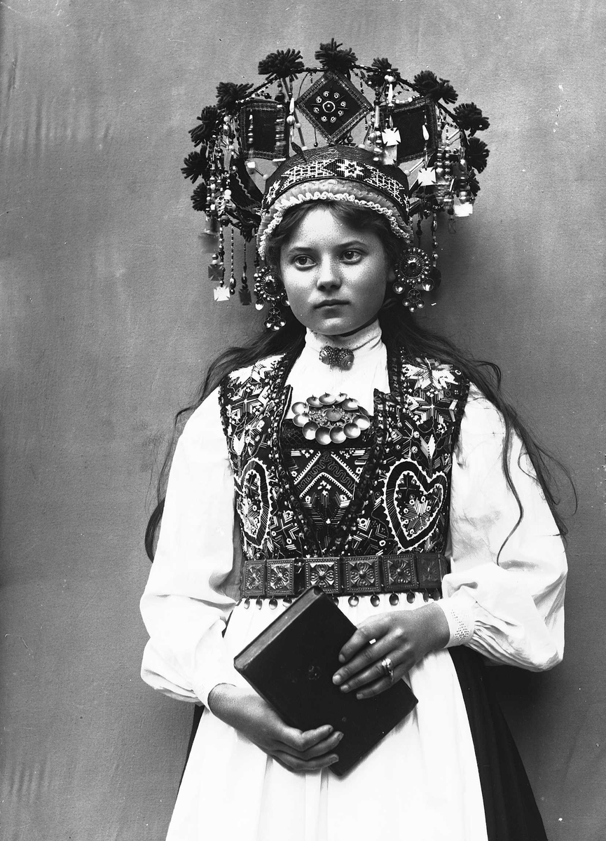 Solveig Lund, Studiofotografi av kvinne med brudedrakt og brudekrone. Stående med salmebok/bibel i hånden. 3/4 dels utsnitt. Vendt mot høyre. Ser ut av bildet.