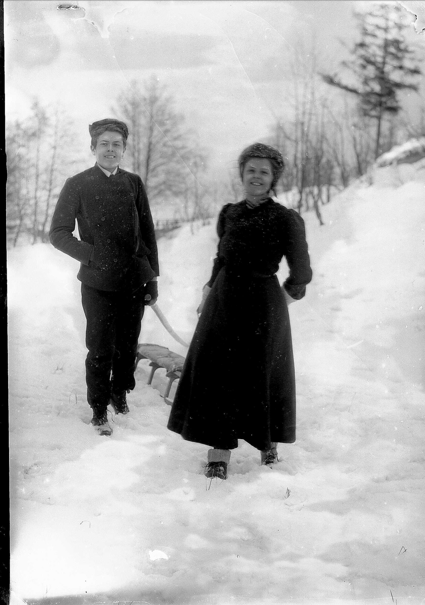 Solveig Lund, Mann og kvinne på tur i snødekt landskap. De drar en kjelke etter seg.