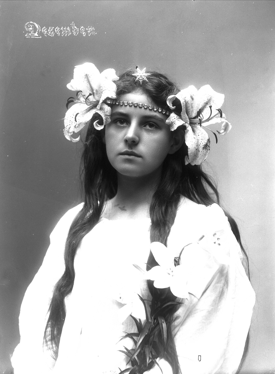 Solveig Lund, Studioportrett av kvinne i drakt med smykker og blomster i håret.