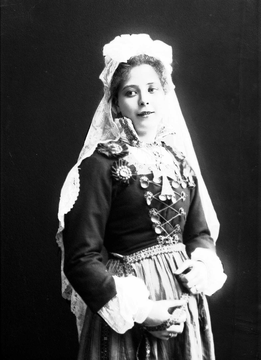 Solveig Lund, Studioportrett av kvinne i drakt og slør.I hendene holder hun et bånd.
