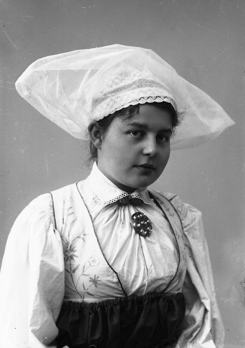 Solveig Lund, Studioportrett av kvinne i drakt og slørliknende lue.