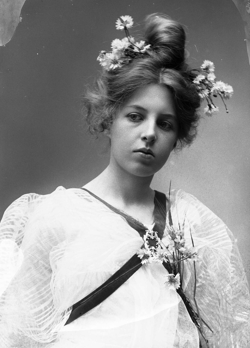 Solveig Lund, Studioportrett av kvinne i kostyme og oppsatt hår - hvit overdel og blomster i håret.