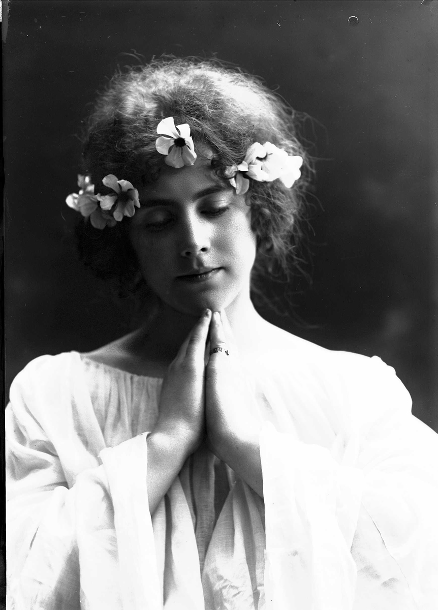 Solveig Lund, Studioportrett av kvinne i kostyme og oppsatt hår - hvit overdel og blomster i håret.