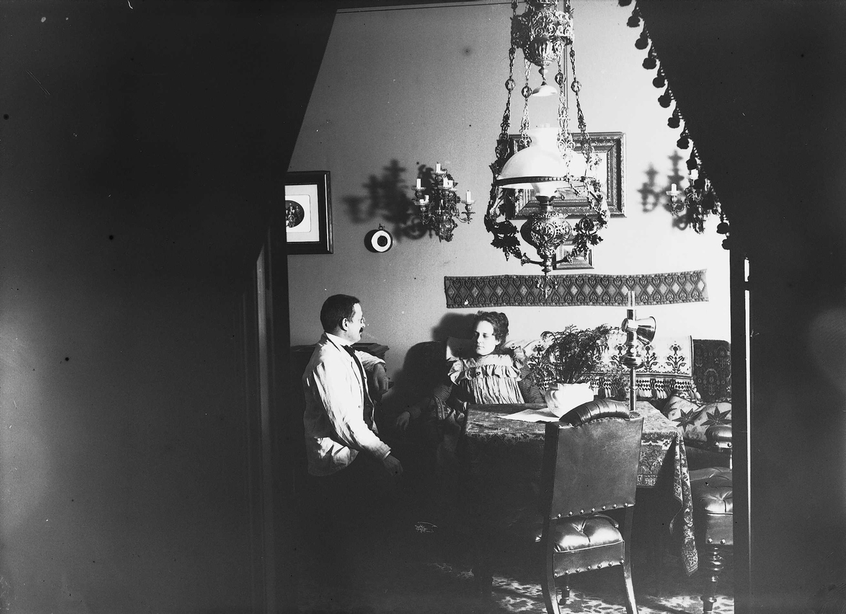 Axel Quinsgaard Wiborg, Axel Q. Wiborg og Edle Wiborg sitter ved bord i stue, Oslo, 1899.