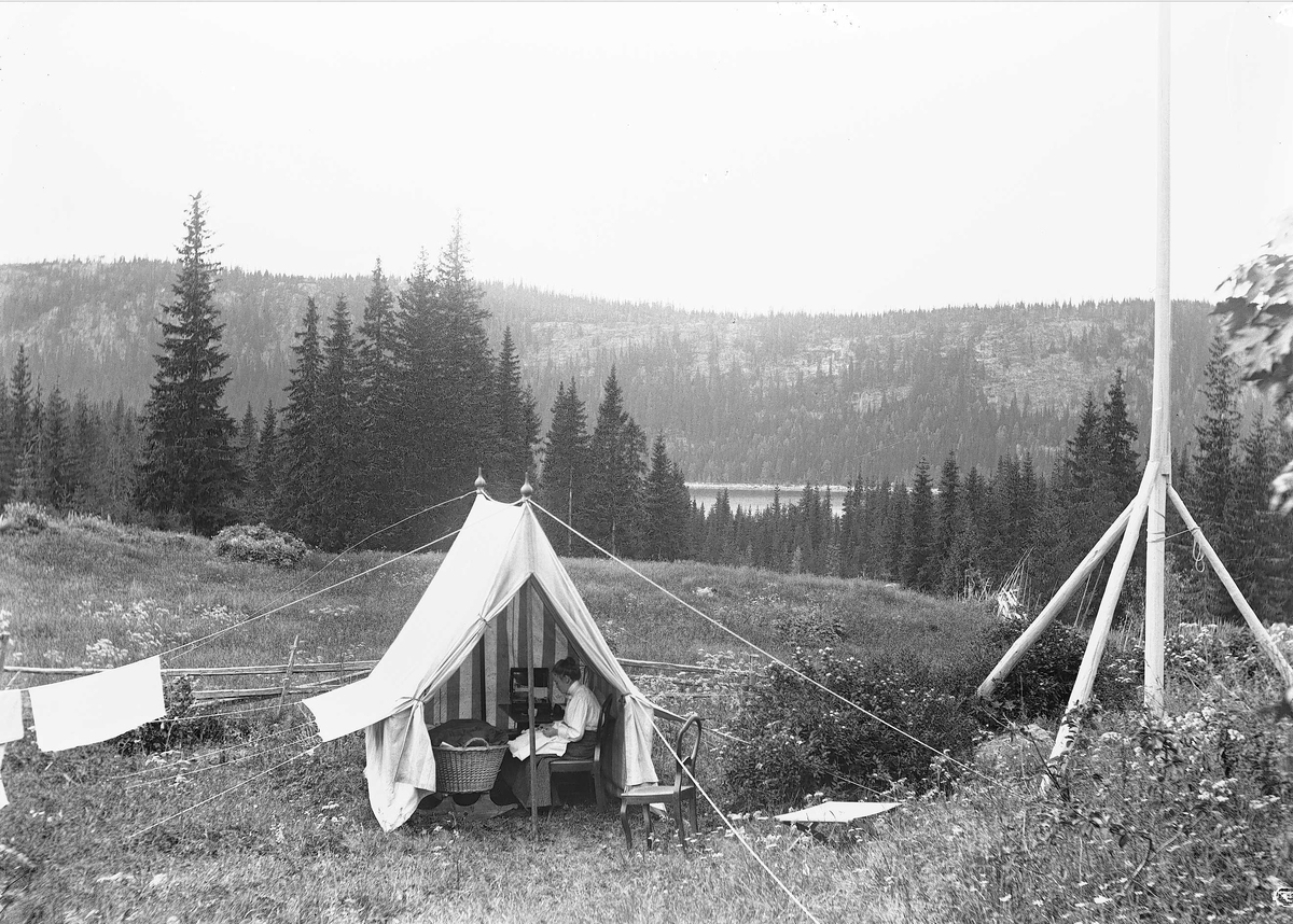 Axel Quinsgaard Wiborg, Margrethe Q. Wiborg sitter i telt med kurv ved Holoa seter, Hadeland, Jevnaker, Oppland, 1903. Utsikt til Skarvvannet.
