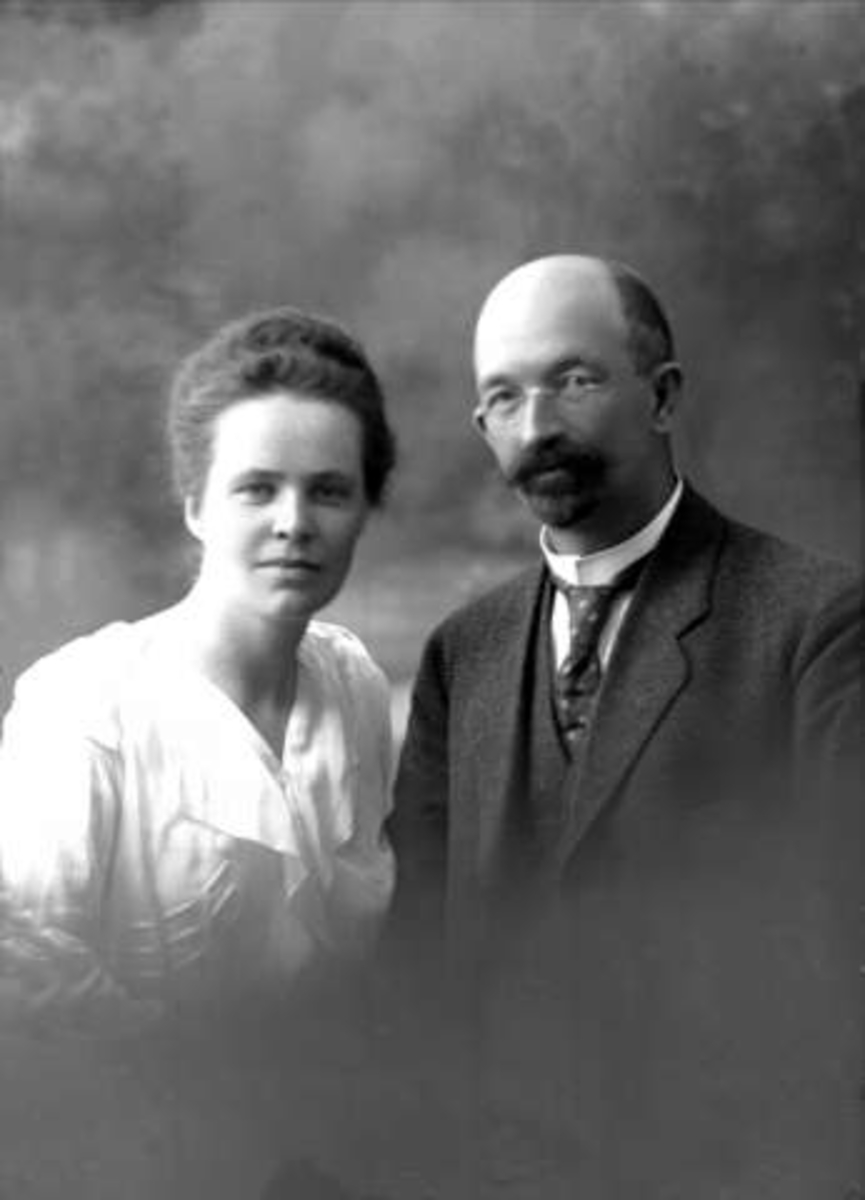 Gustav Borgen, Gruppeportrett, ektepar, lys drakt og dress. Briller og skjegg. Avdelingssjef Horgen.