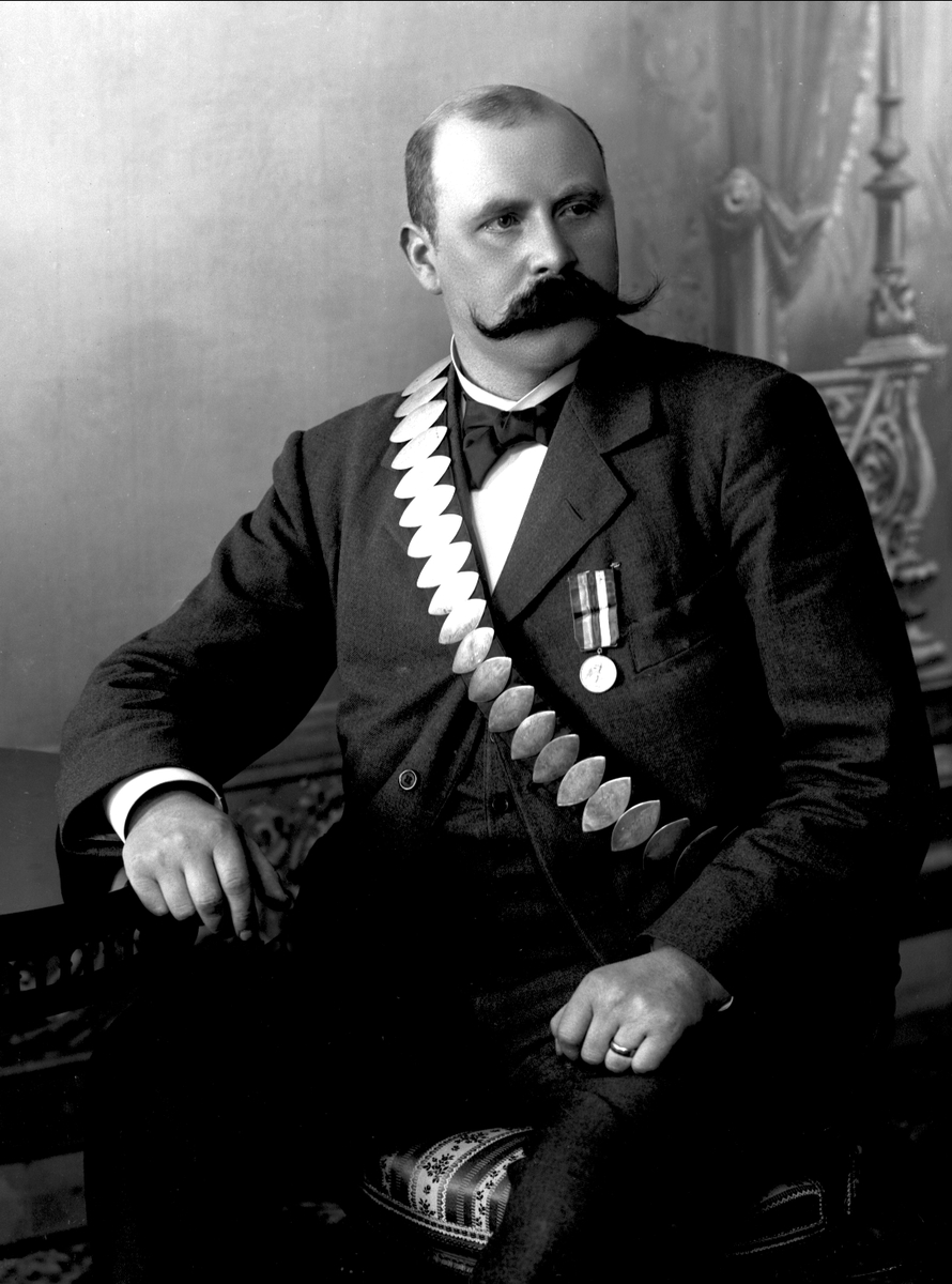 Gustav Borgen, Portrett, mann med bånd med premieplaketter, skyting. Kongebelte til Skydeselskapet Skarpskytten(?).