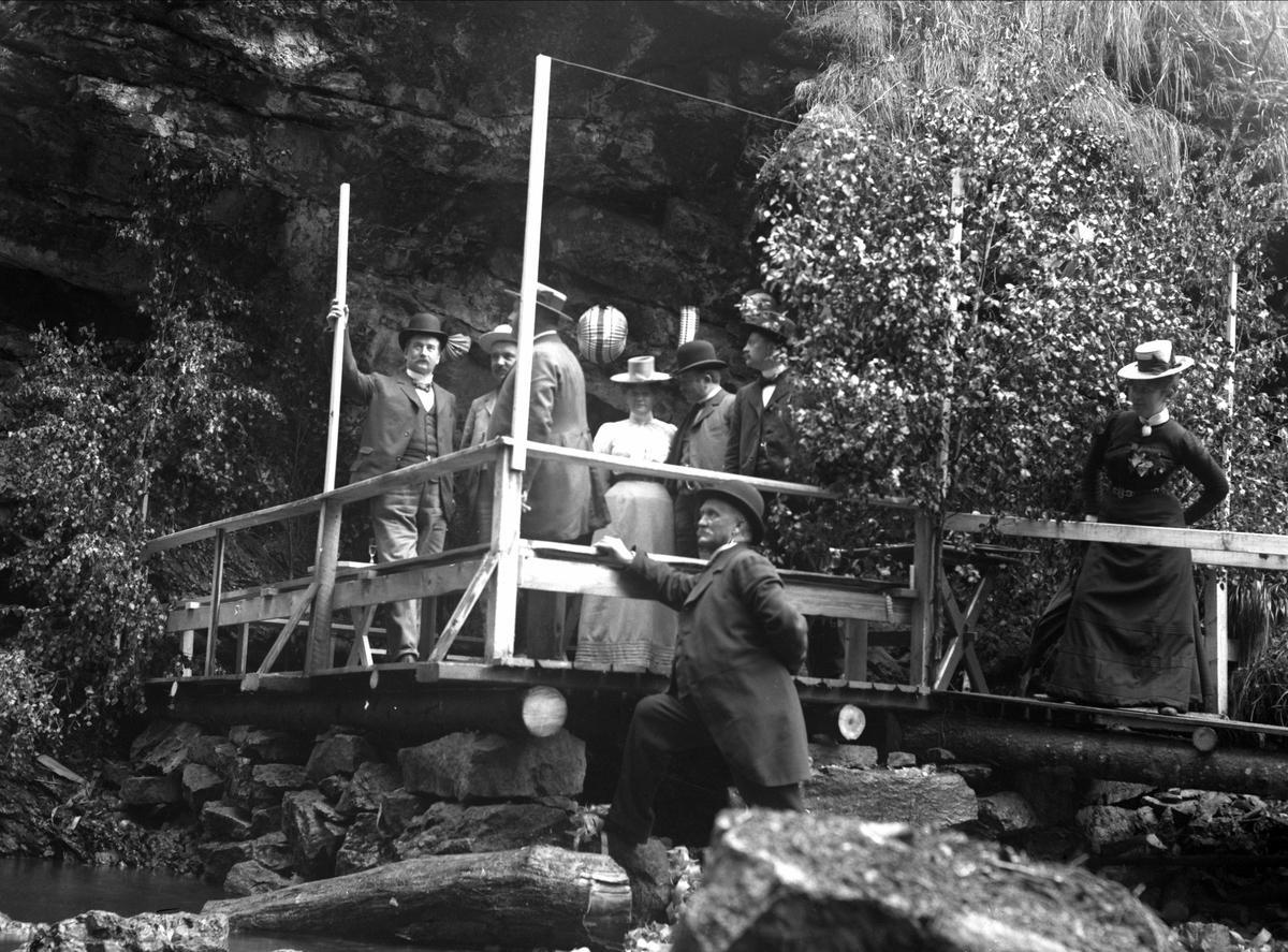 Gustav Borgen, Gruppe mennesker stående på plattform/brygge i tre. Fjell/berg i bakgrunnen.