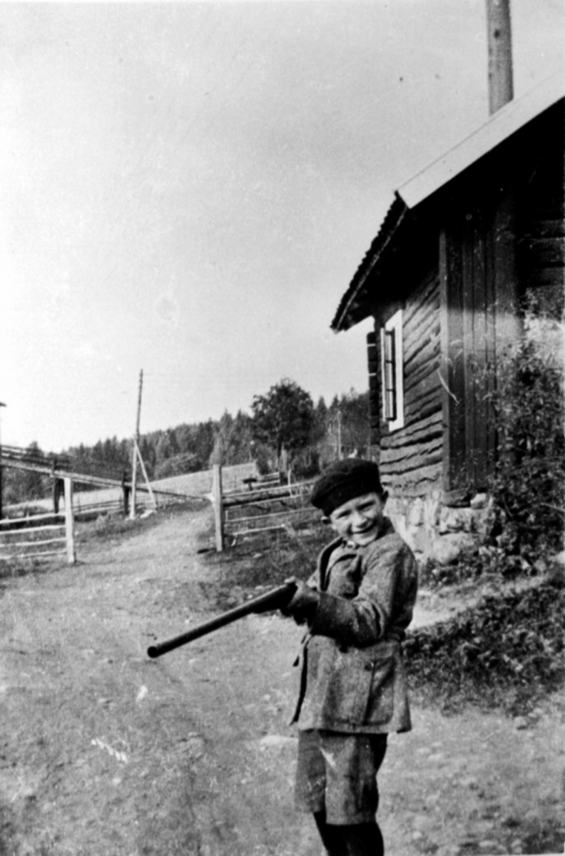 Anno Domkirkeodden, Gerhard Vien f.1917 med gevær utenfor gammelt hus på Grimsrud, Helgøya.