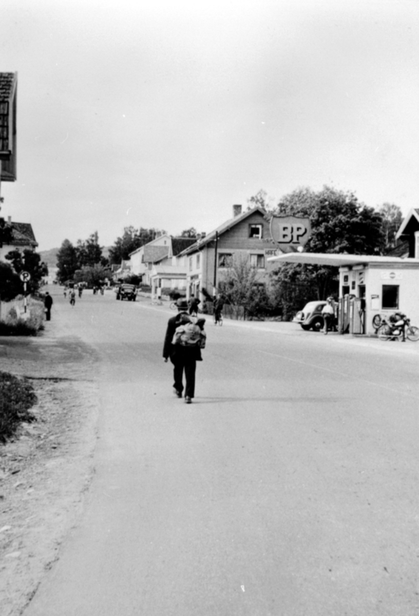 Anno Domkirkeodden, Storgata, Moelv, folk og biler, bensinstasjon, mann med ryggsekk.