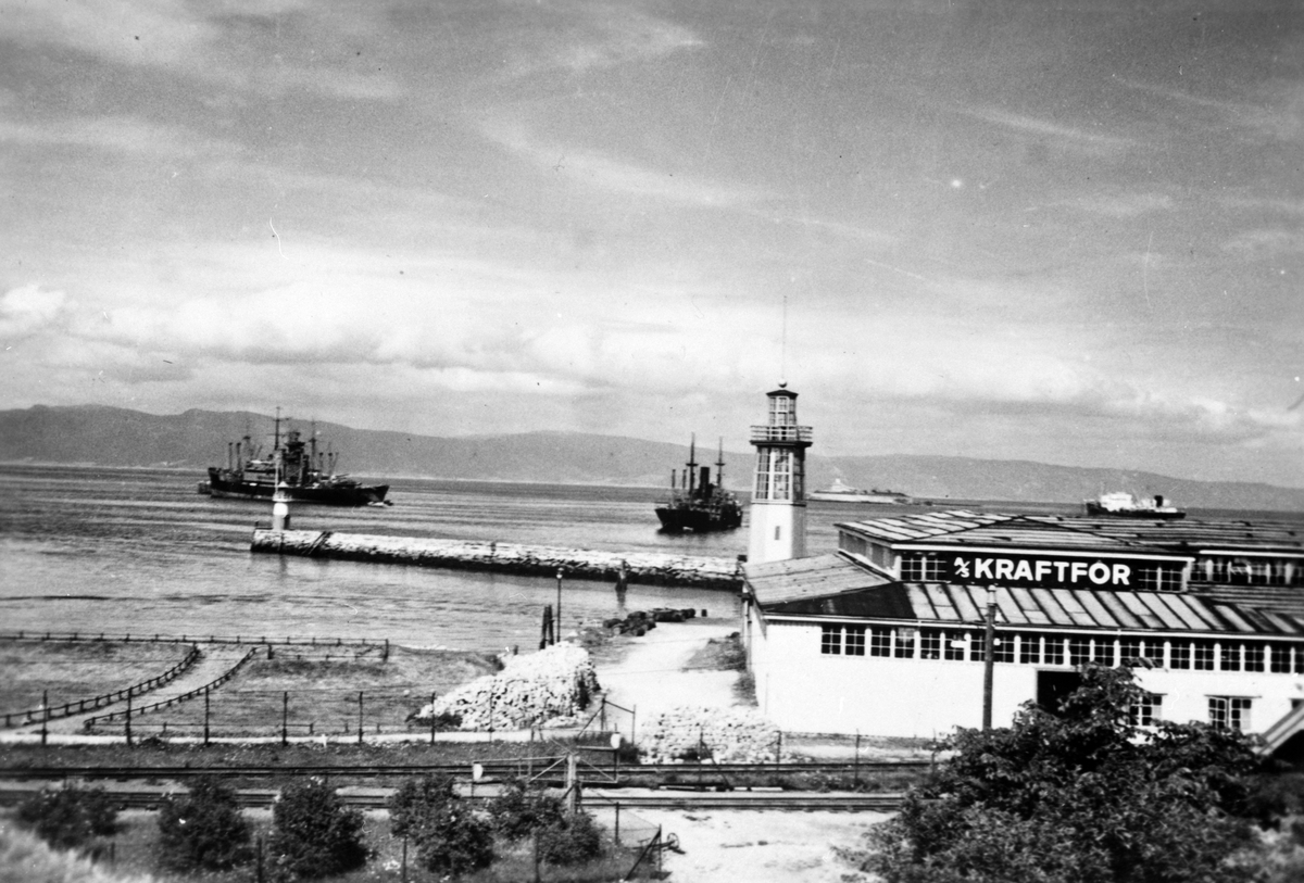 Håkon Prestkværn, Trondheim havn, våren 1940. 2. verdenskrig.Til venstre i bildet sees det tyske slagskipet Gneisenau med verkstedsskipet Huascaran fortøyd langs siden. Gneisenau ble torpedert 20. juni 1940 av den britiske undervannsbåten Clyde og søkte nødhavn i Trondheim. Etter midlertidige reparasjoner med assist…
