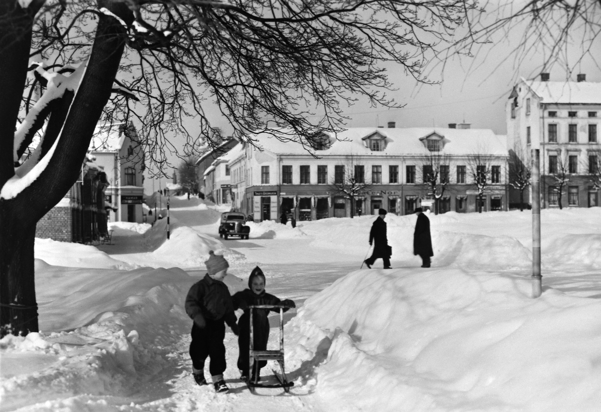 Anno Domkirkeodden, GRUPPE: 2 BARN MED SPARK, STRANDGATEPARKEN, I BAKGRUNNEN STORTORGET MED ÅSGÅRDEN, HØYE BRØYTEKANTER, VINTER