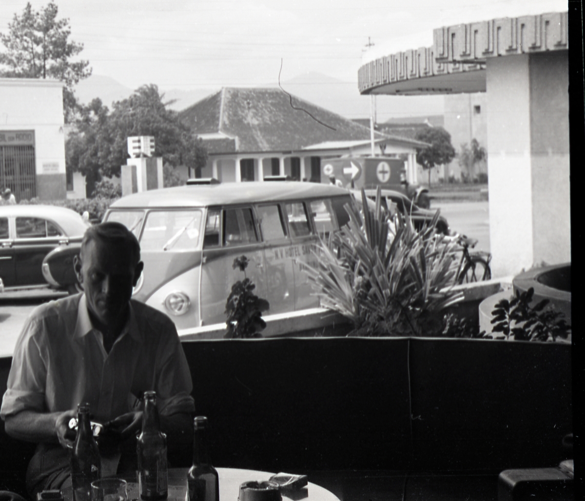 Jan Herman Linge, Mann holder i et kamera ved et bord. Sansynligvis i kantina på Hotel Savoy Homann, Bandung, Indonesia.