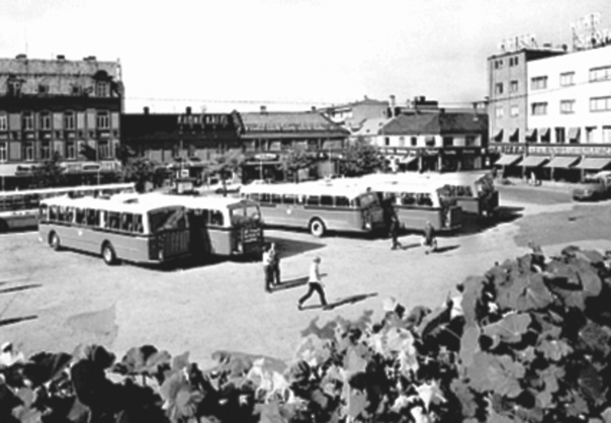 Anno Domkirkeodden, OVERSIKT ØSTRE TORG FRA RUTEBILTAKET, BLOMKARSE I FORGRUNNEN, FOLK, BUSSER MOT S. RUSTAD