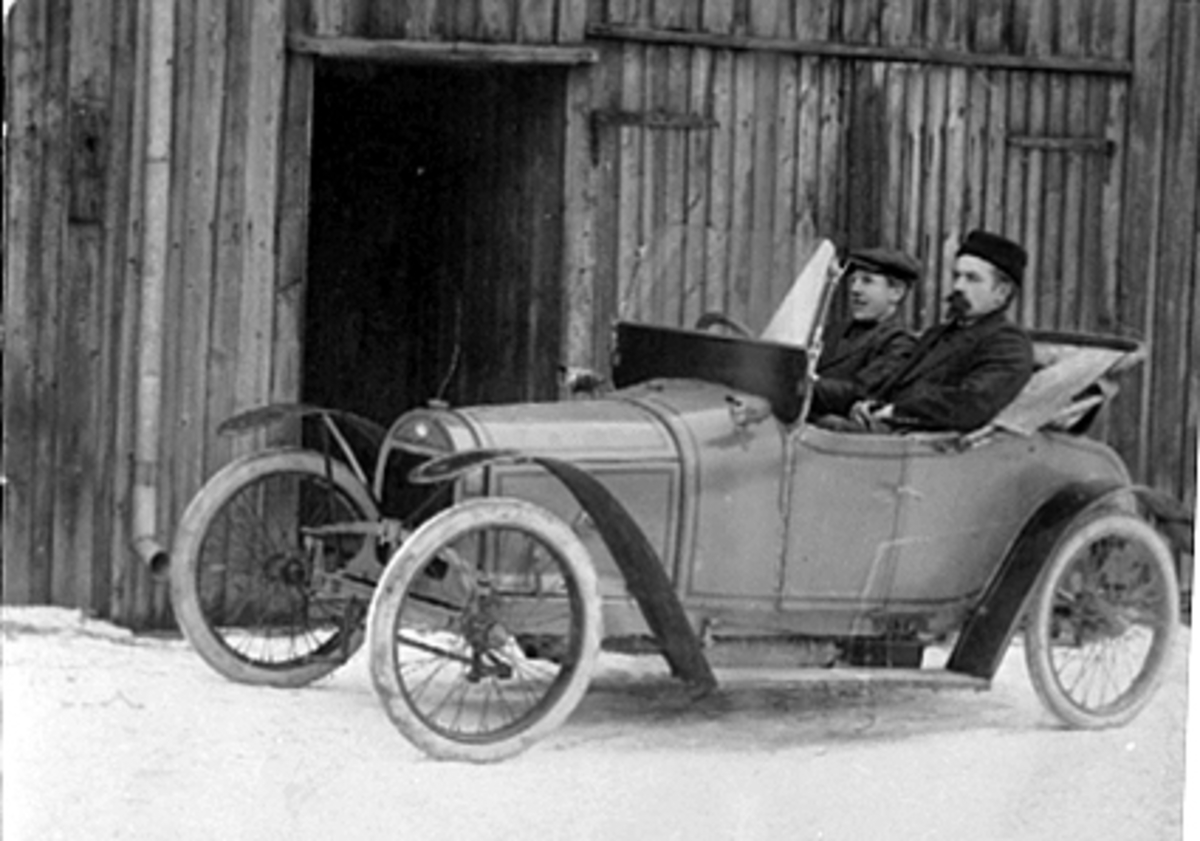 Anno Domkirkeodden, HAMARS FØRSTE BIL? MARTIN OUSTAD OG OLAF WALBERG VED RATTET, "BABY" BILMERKE, TATT UTENFOR OUSTADS FØRSTE VERKSTED. BILEN ER BYGGET I FRANKERIKE AV FIRMAET SA ANCIENS ETABLISSEMENTS FOURNIER FØR FØRSTE VERDENSKRIG. MODELLEN BABY HADDE ENTEN 1 CYLINDERS MOTOR PÅ 6-8 HK. ELLER 10 HK.