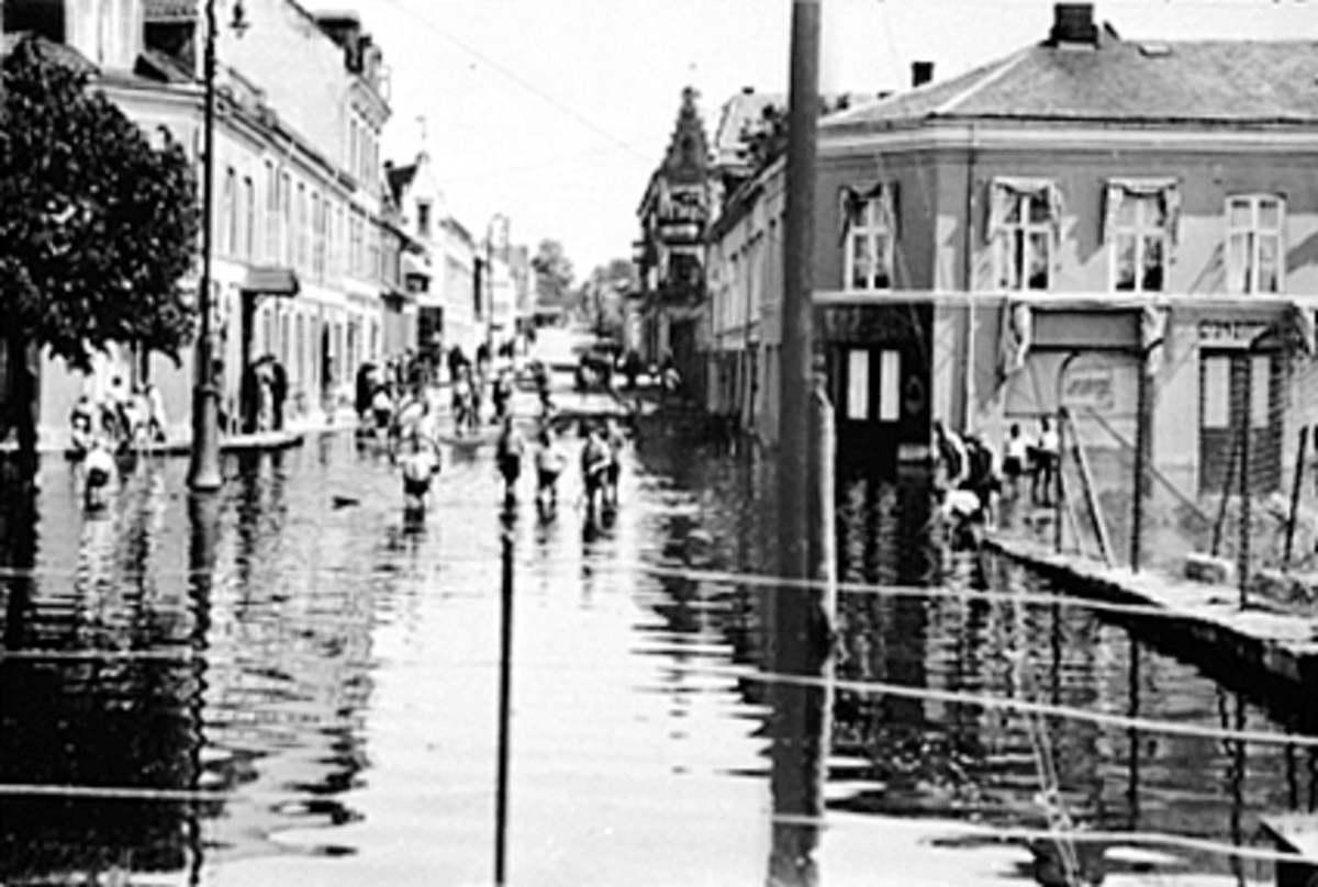 Anno Domkirkeodden, BARN LEKER I FLOMVANN 1927, FRA JERNBANEBRUA OPP ENGGATA, VICTORIA HOTELL TIL VENSTRE, BAKER O. JOHANNESSEN TIL HØYRE