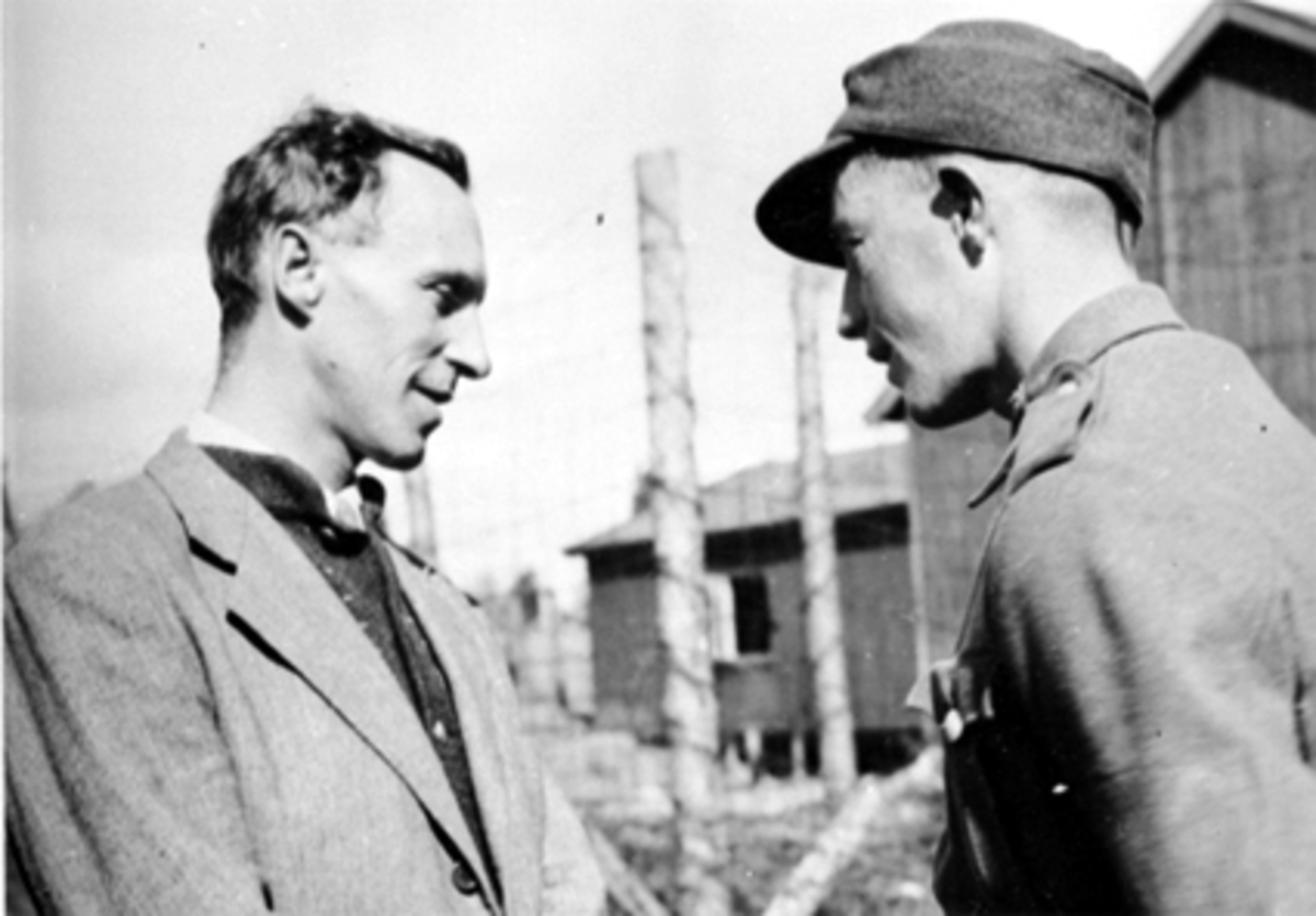 Anno Domkirkeodden, 17 MAI. ADV. SVERRE KNUDSEN I SAMTALE MED EN SOLDAT, BRAKKE MED HØYT GJERDE RUNDT, FANGELEIR?SE HHB 10122