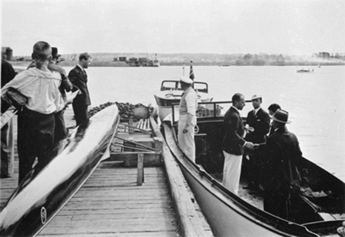 Anno Domkirkeodden, MOTORBÅTER OG DOBBEL-SCULLER VED HAMAR BRYGGE, FOLK, I BAKGRUNNEN JERNBANEBRYGGA