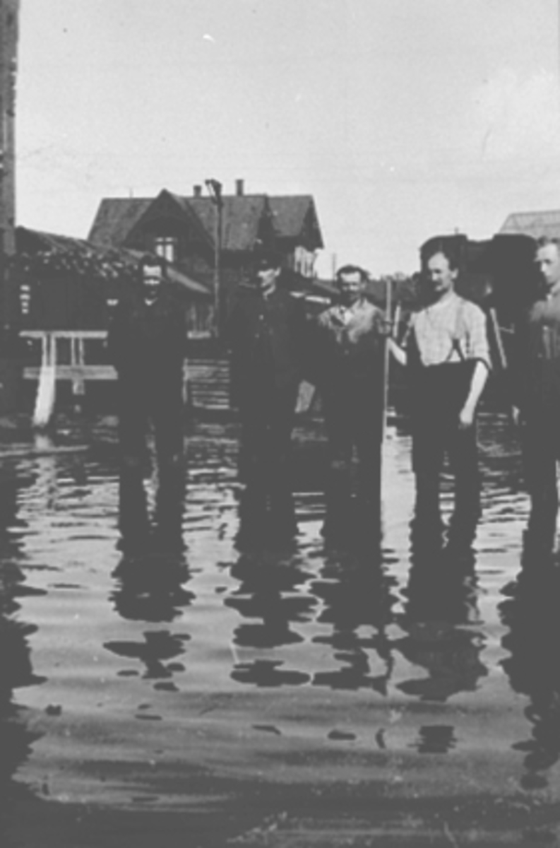 Anno Domkirkeodden, Mjøsflom 1927. Hamar Jernbanestasjon. Gruppe 5 arbeidere ved Jernbaneverkstedet står i flomvannet. Mannen med skyggelue er lokomotivmester Jens Kraft Lund, de øvrige ukjente.