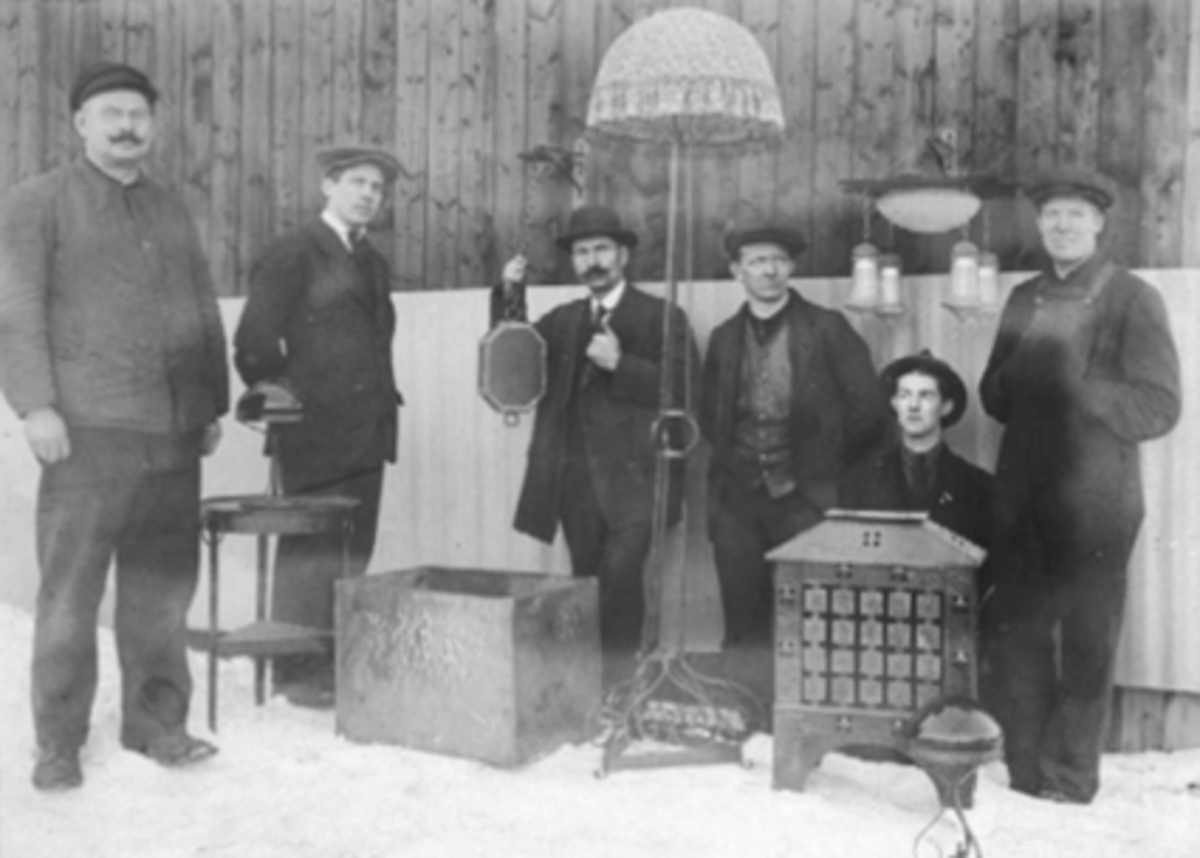 Anno Domkirkeodden, GR: 6 MENN UTENFOR KUNSTSMED EINAR NORDRUMS LOKALER, BIOGRAFENNordrum hadde utsalg i kjelleren i Biografen. Kunstsmie. Han flyttet senere til Yngelingen i Kirkebakken. Utstilling av forskj. gjenstander som Einar Nordrum laget. Arne Lommerud med hatt. Se Karin Nord Syverinsens bok Påfuglen i Parken …