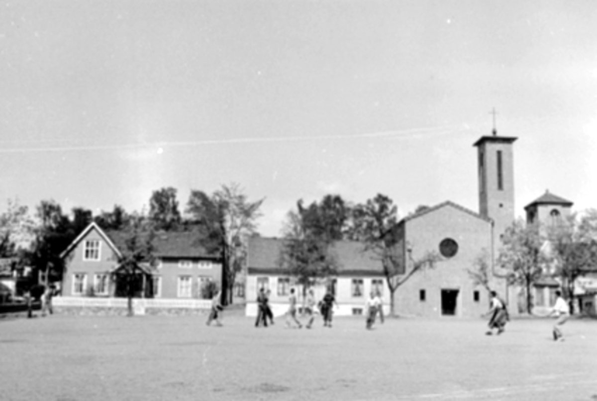 Anno Domkirkeodden, Det katolske kvartalet mot Vestre Torg, Presteboligen t. v. for kirken ble kjøpt i 1937 og solgt i 1973 og erstattet av et nybygg året etter. Rud-villaen ytterst t. v. ble kjøpt i 1971. Elever fra Hamar katedralskole spiller fotball i forgrunnen.