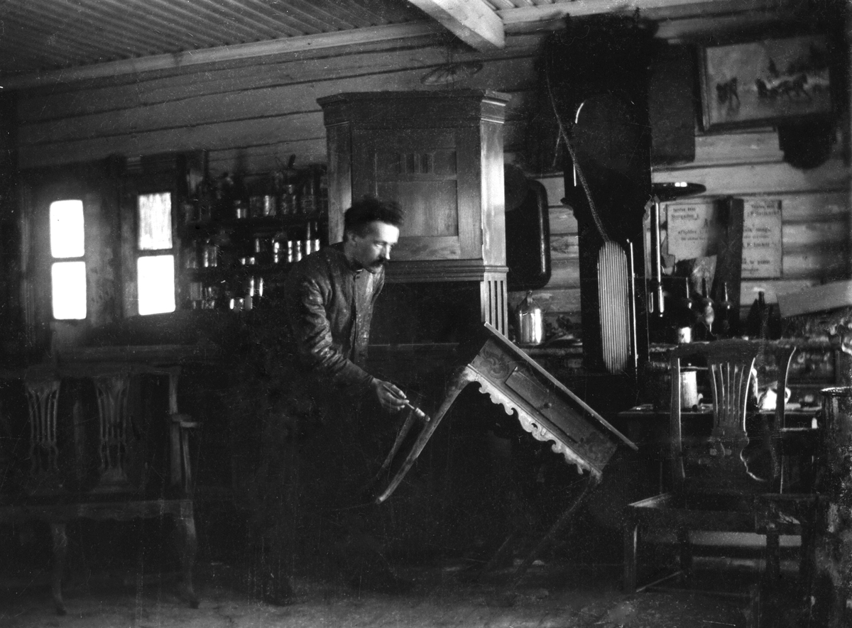 Anno Domkirkeodden, INTERIØR MALERVERKSTED, HÅNDVERKER JOHAN ELFSTEDT MALER ET BORD, i sitt verksted i POSTHUSGÅRDEN, GRØNNEGATA 52 i Hamar.