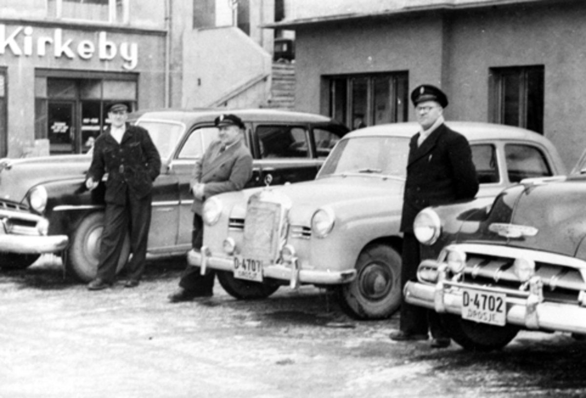 Anno Domkirkeodden, HAMAR TAXISENTRAL. DROSJEHOLDEPLASSEN PÅ ØSTRE TORG, DROSJEEIERE MED BILER. FRA VENSTRE KRISTIAN MIKKELSEN, HARALD LARSEN OG PETTER HEGESEN, BILER FRA VENSTRE: DODGE 1951-52 MODELL 7-SETER, MERCEDES-BENZ D-4707, CHEVROLET1952 MODELL D-4702