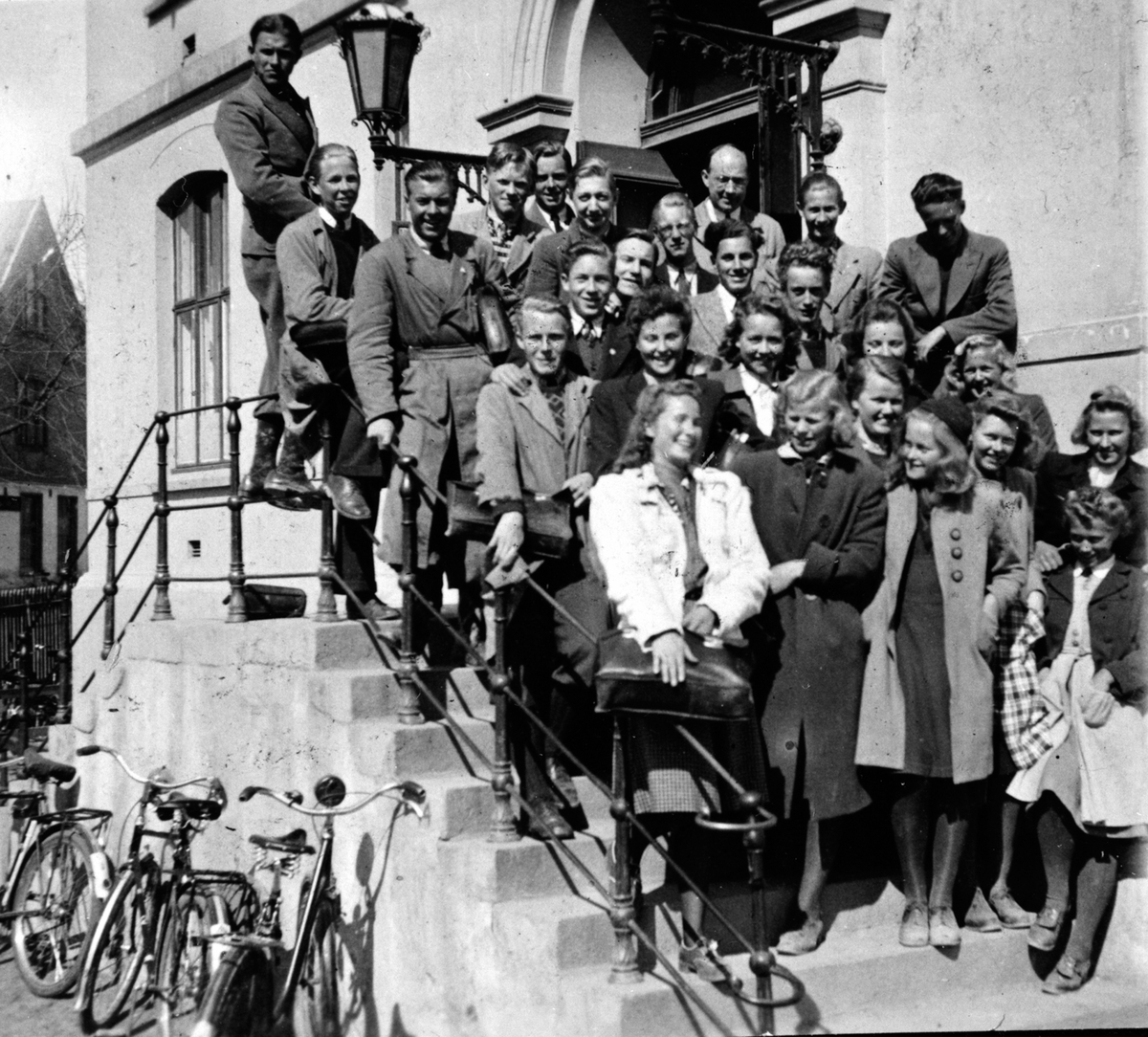 Anno Domkirkeodden, HAMAR KATEDRALSKOLE. 1 ENGELSK/LATINKLASSEN HØSTEN 1940. UNDERVISNINGEN FOREGIKK PÅ HAMAR FOLKESKOLE, MIDTBYEN SKOLE. LEKTOR HENRY O. DØRUM SAMMEN MED ELEVENE PÅ STORSKOLETRAPPA.