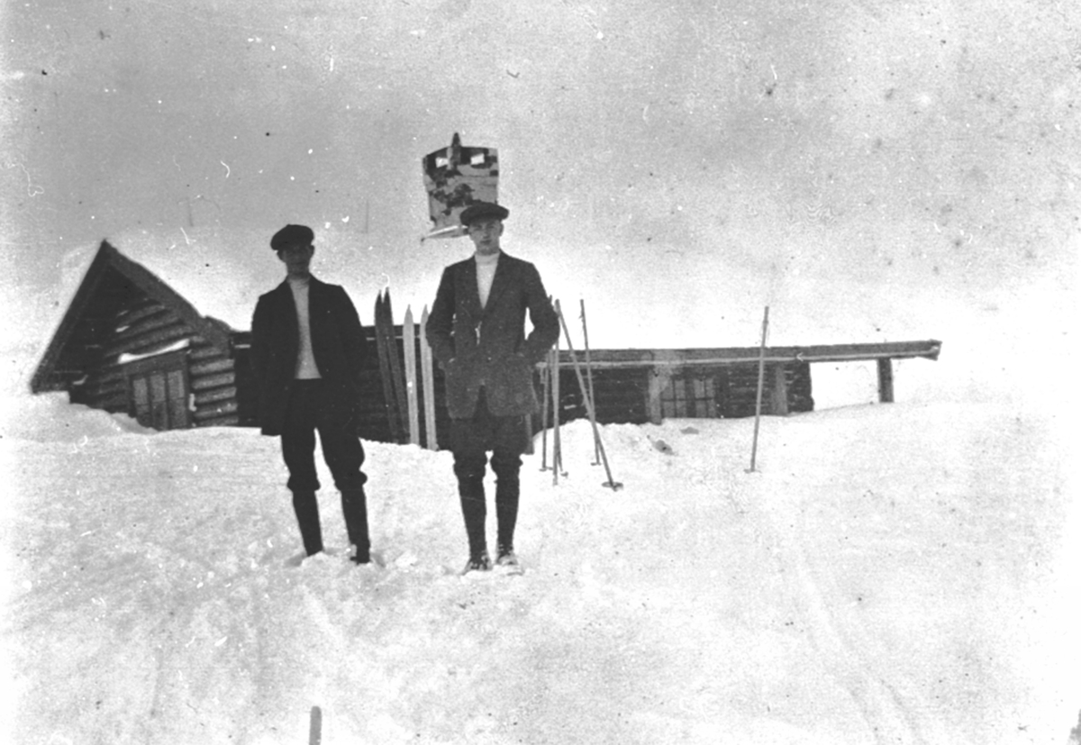 Anno Domkirkeodden, To menn med ski utenfor hytte. Familien Løken, påskeferie, fritid.