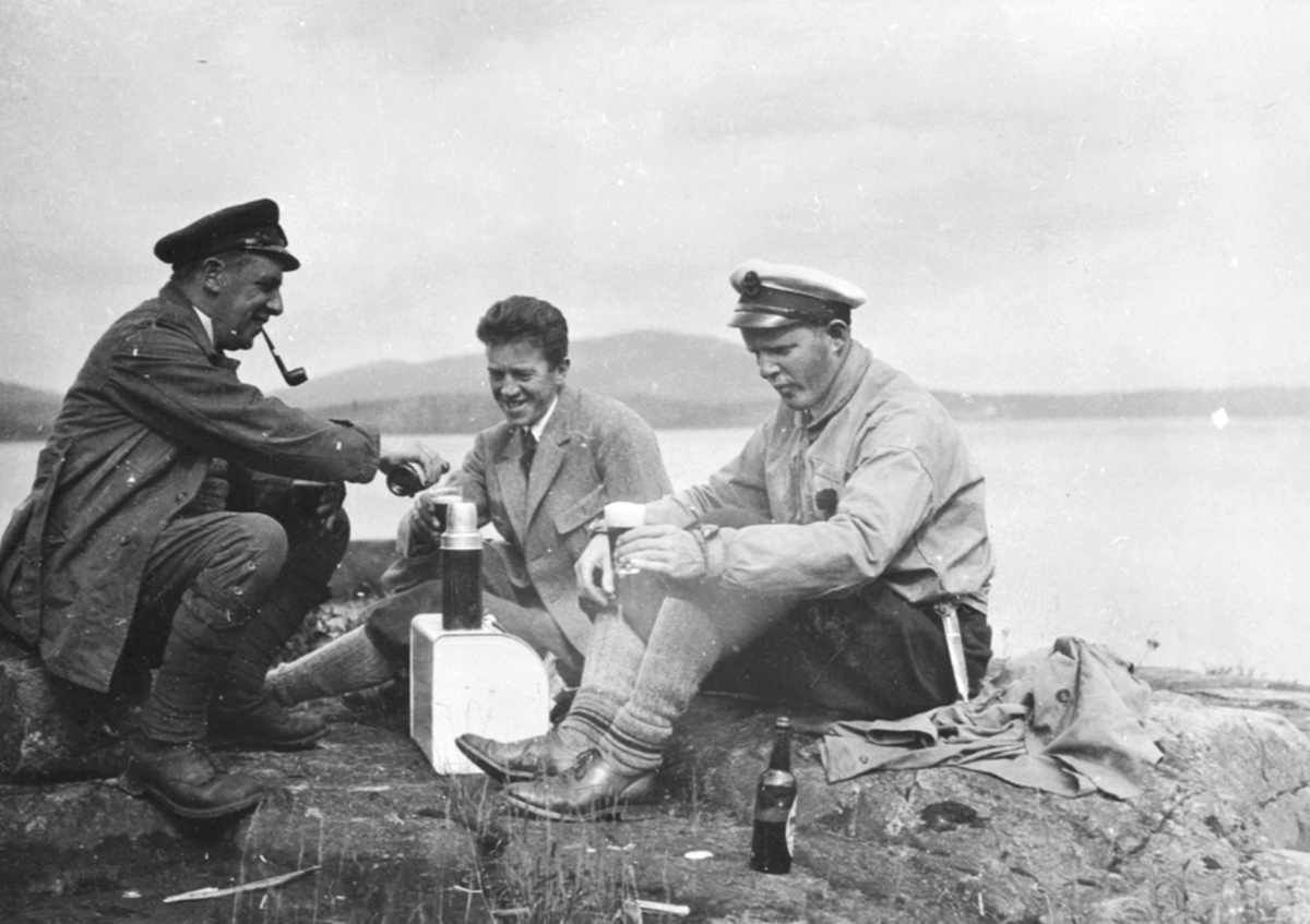 Anno Domkirkeodden, Tre menn raster i strandkanten. Fra venstre er Nickelsen, Bjørnerud, tannlege Karl Løken med skyggelue og slirekniv. Flasker og termos.