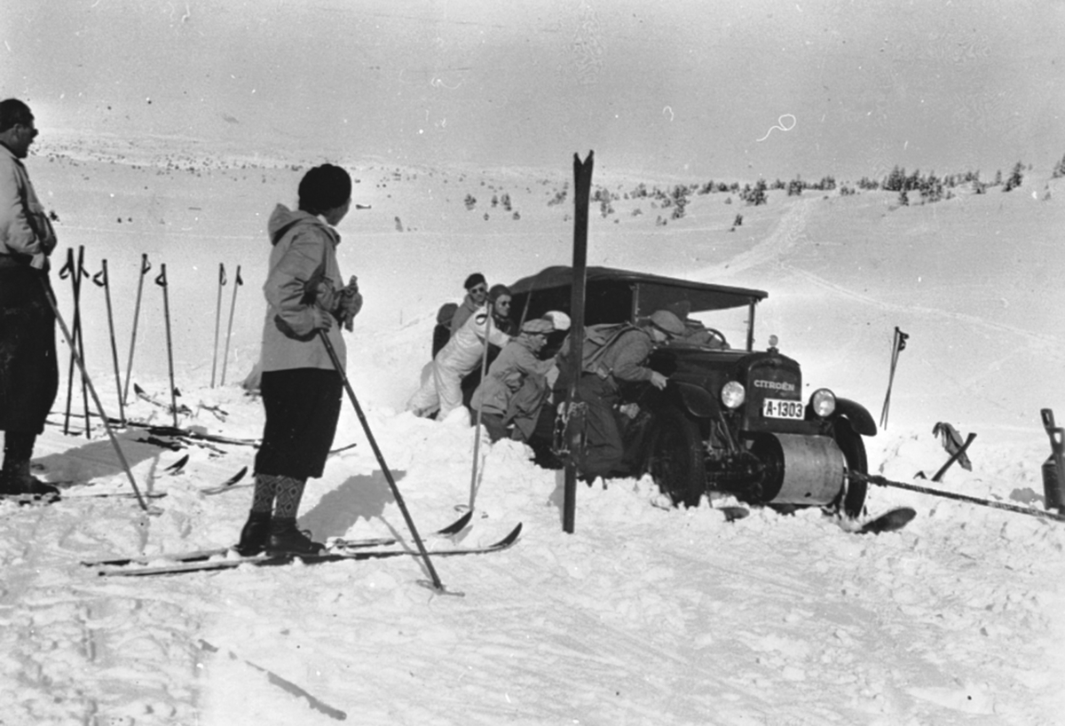 Anno Domkirkeodden, Beltebil, en Citroen med A-1303 dyttes av folk, på tur til fjellet. Folk på ski.