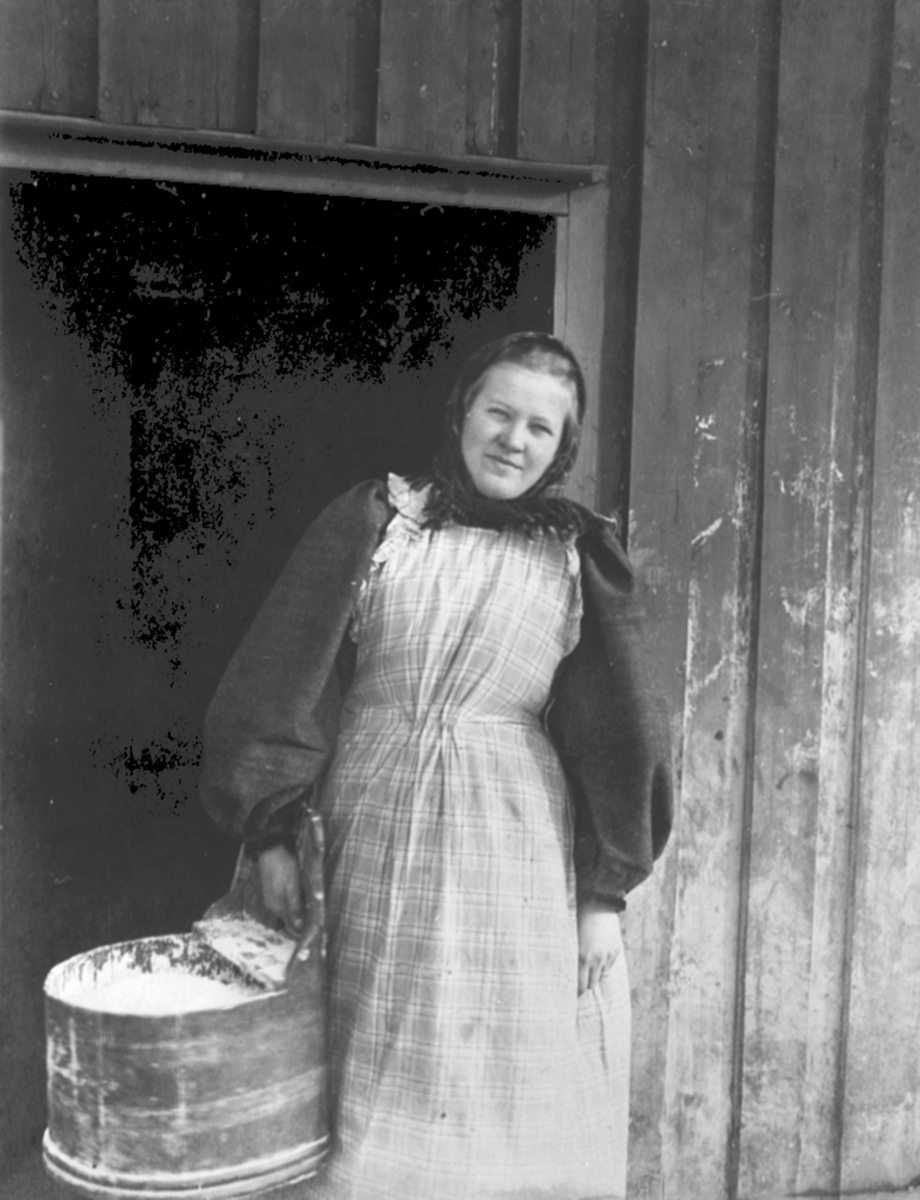 Anno Domkirkeodden, Mimi Løken f.1876 i fjøsdøra på Løken østre, Veldre, Ringsaker. I budeieklær med mjølbutt.