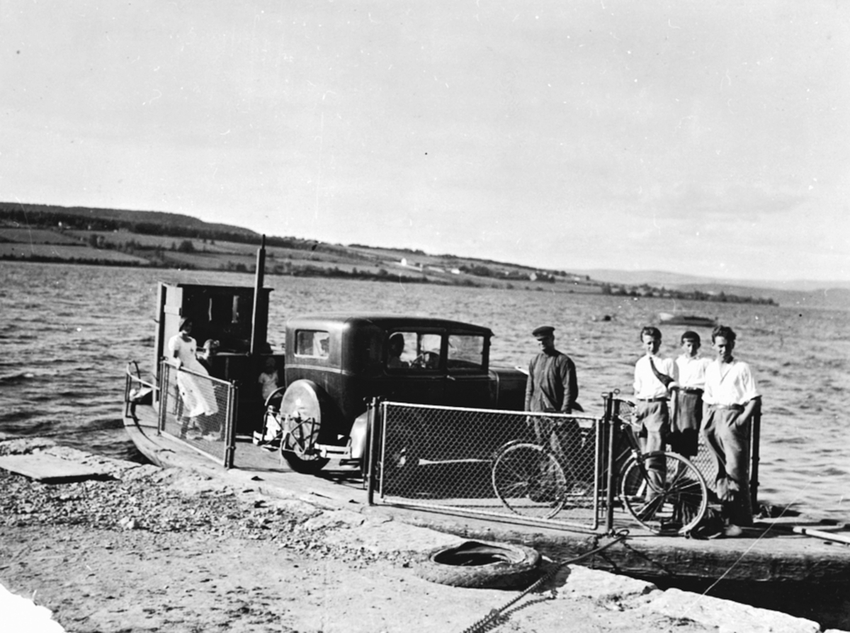 Anno Domkirkeodden, Ferja "Helgøya" ved Sundsbrygga. Ved styrhuset er Olaug Sund f.1915, Karen Røste f.1917. Ved bilen er Karl Sund (1890-1962). De tre karene i hvit skjorte er fra venstre Erling Rønning, Johan Schwenke, Georg Gåserud f.1914.