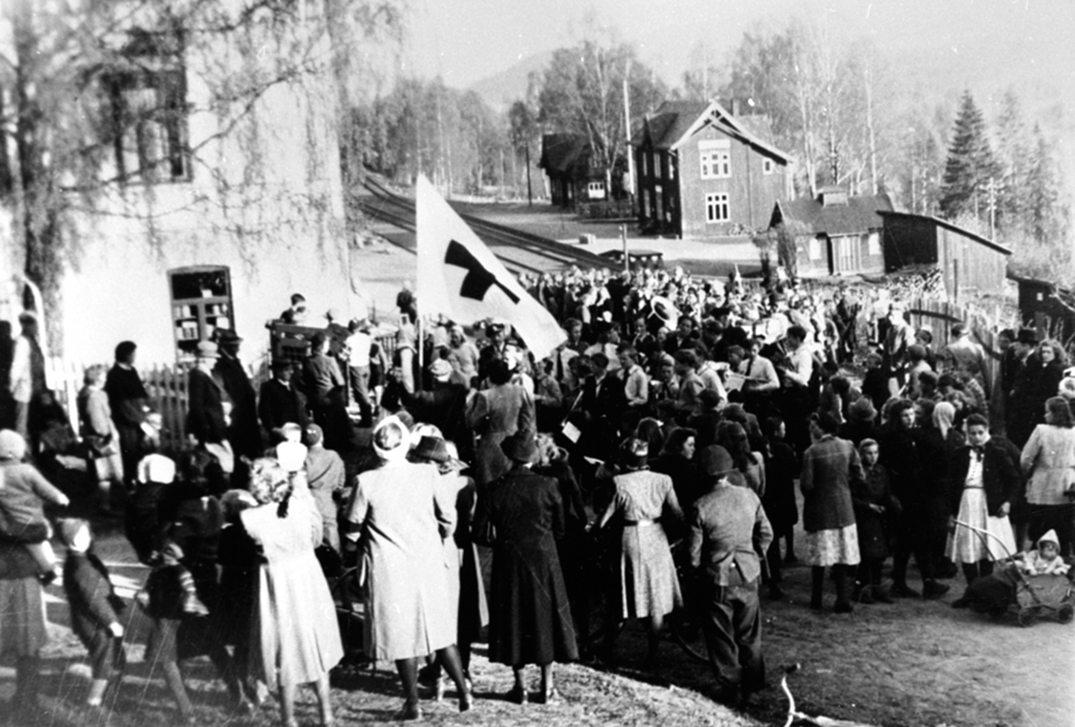 Anno Domkirkeodden, Røde Kors opptog på Veldre jernbanestasjon, mye folk, flagg.