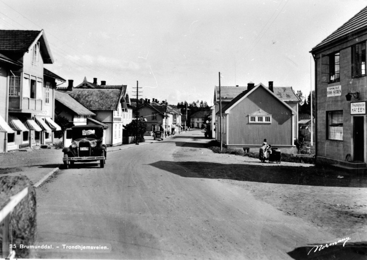Anno Domkirkeodden, Oversikt, Furnesvegen, Brumunddal. Bil i gata D-3370. Fra venstre Broberg, Jevne, Kvislien, Midttun, Helgeby lille, Stampen, Heimdal, Elvarheim, Frelsestemplet, Promenadekafeen. Postkort "Trondhjemsveien, Brumunddal, Nr. 35. Foto Normann. Ford A 1930. I Norges Bilbok 1935 står D-3370 som Ford perso…