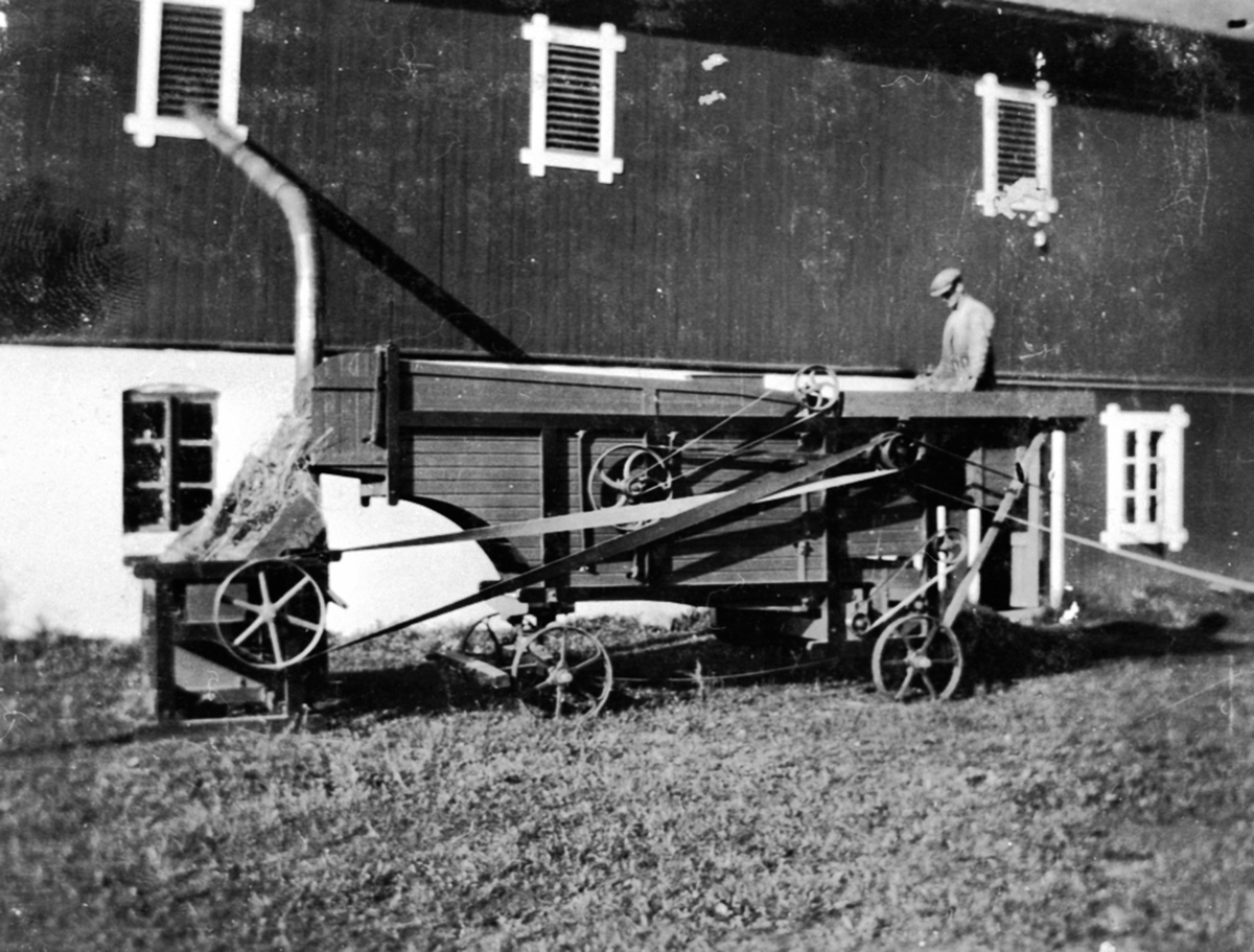 Anno Domkirkeodden, Globus treskeverk med elektrisk motor og drivreim. Innblåsingsrør til låven. Buttekvern gård, Brumunddal. Arbeider mater verket.