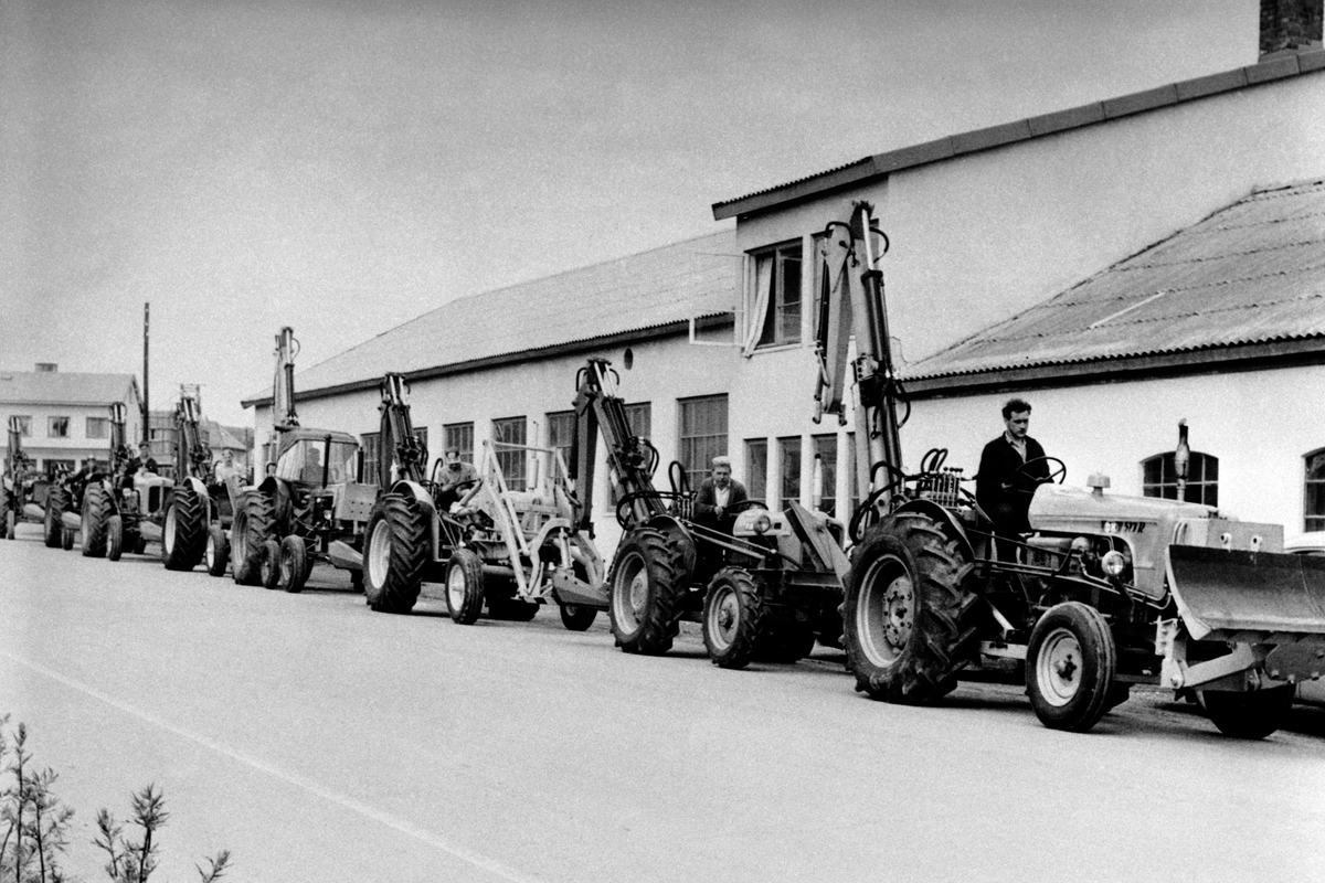 Anno Domkirkeodden, Traktorparade med Hymasmaskiner ved Brumunddal Mekaniske verksted, Hymas A/S. Gravemaskinparade i Nygata, Brumunddal ca. 1960. På traktorgraver til høyre Odddvar Almerud.