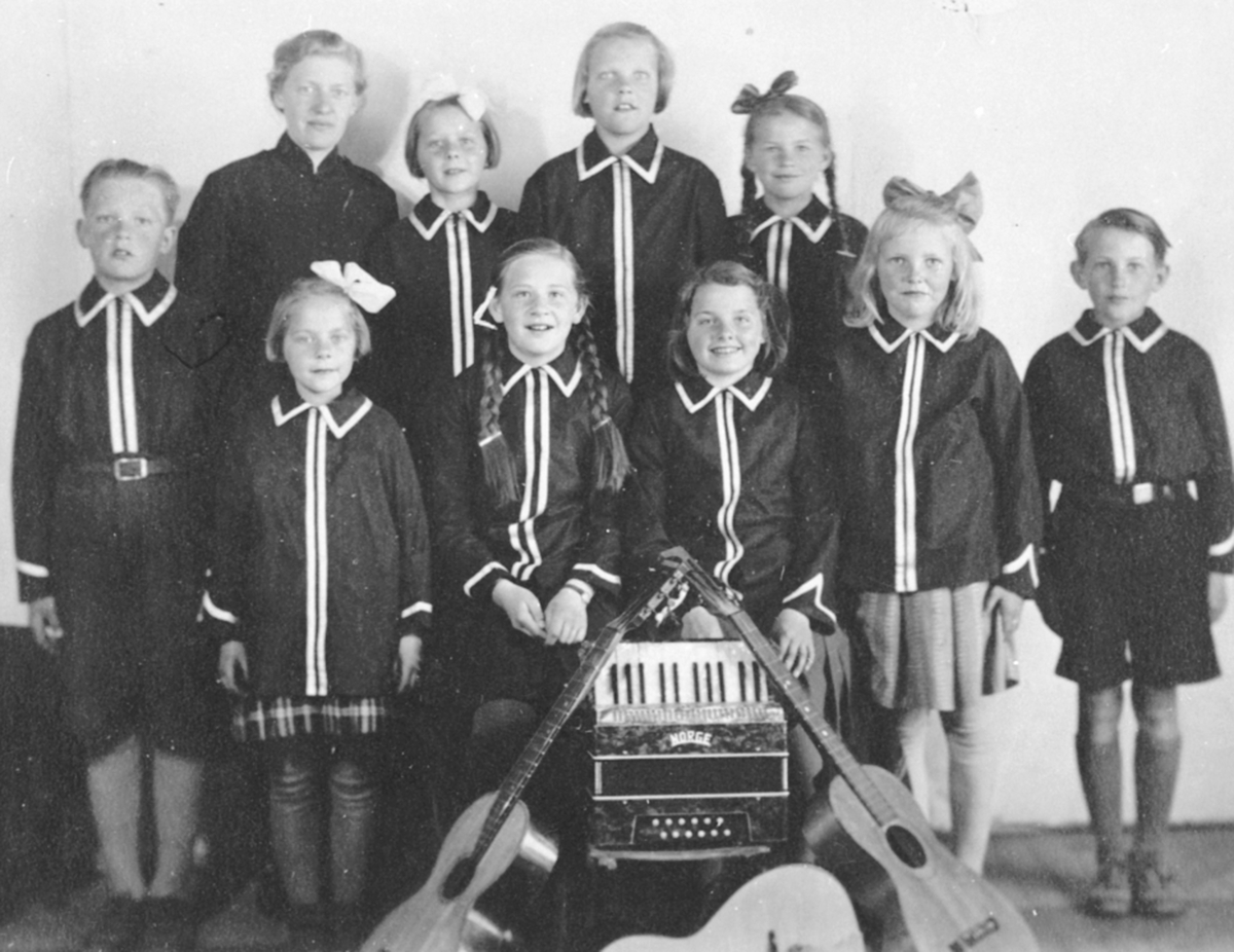 Anno Domkirkeodden, Juniorsoldater og 1 voksen ved Frelsesarmeen i 1942. Trekkspill og gitar i forgrunn. 1 rekke fra venstre er Osvald Holter, Kirsten Skansberg Storsveen, Liv Ingebrigtsen, Magnhild Andersen, Kirsten Holter Andersen, Odd Ingebrigtsen. 2 rekke fra venstre er kaptein Randi Harjo, Anne Marie Skansberg Ny…