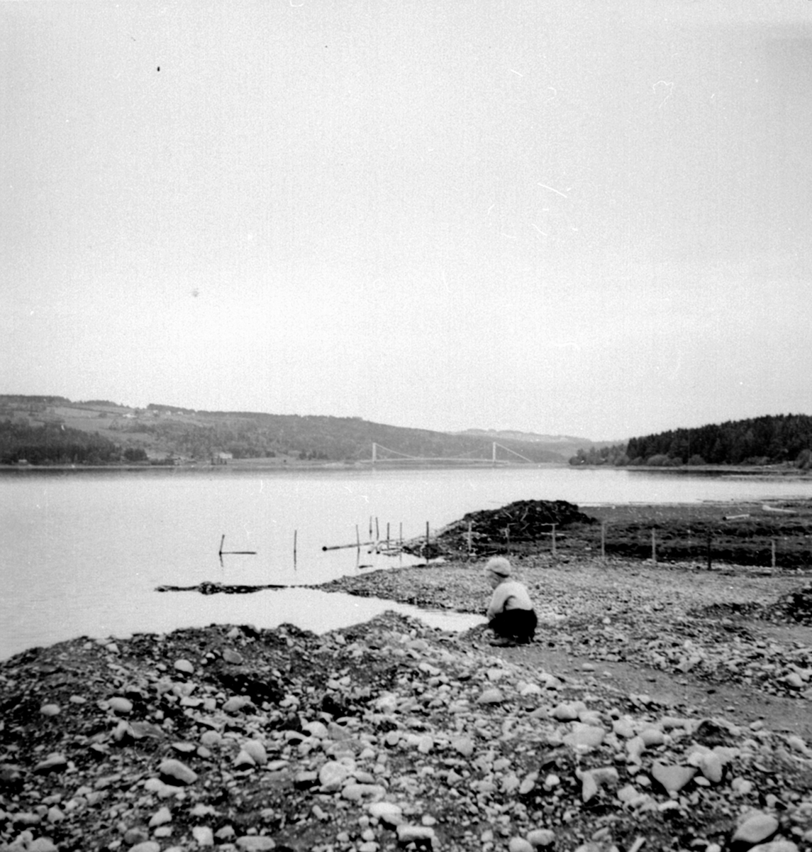 Anno Domkirkeodden, Liten gutt i Mjøskanten nedenfor strandsaga, Framnesbrua i bakgrunn, Brumunddal.