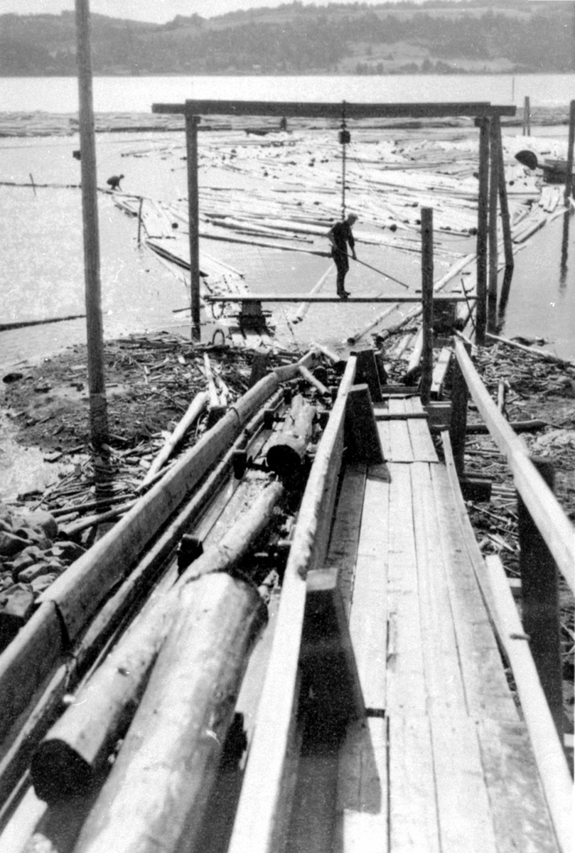 Anno Domkirkeodden, Arbeider drar tømmer opp kjerraten ved Strandsaga, Berger Langmoen A/S, Brumunddal.