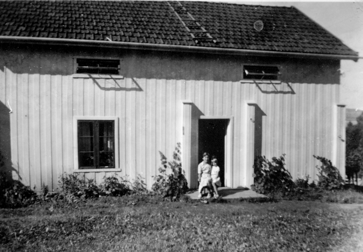 Anno Domkirkeodden, Vestli, Helgøya. Denne bygningen ble revet og ny ble bygd i 1968/69. 2 personer foran huset.