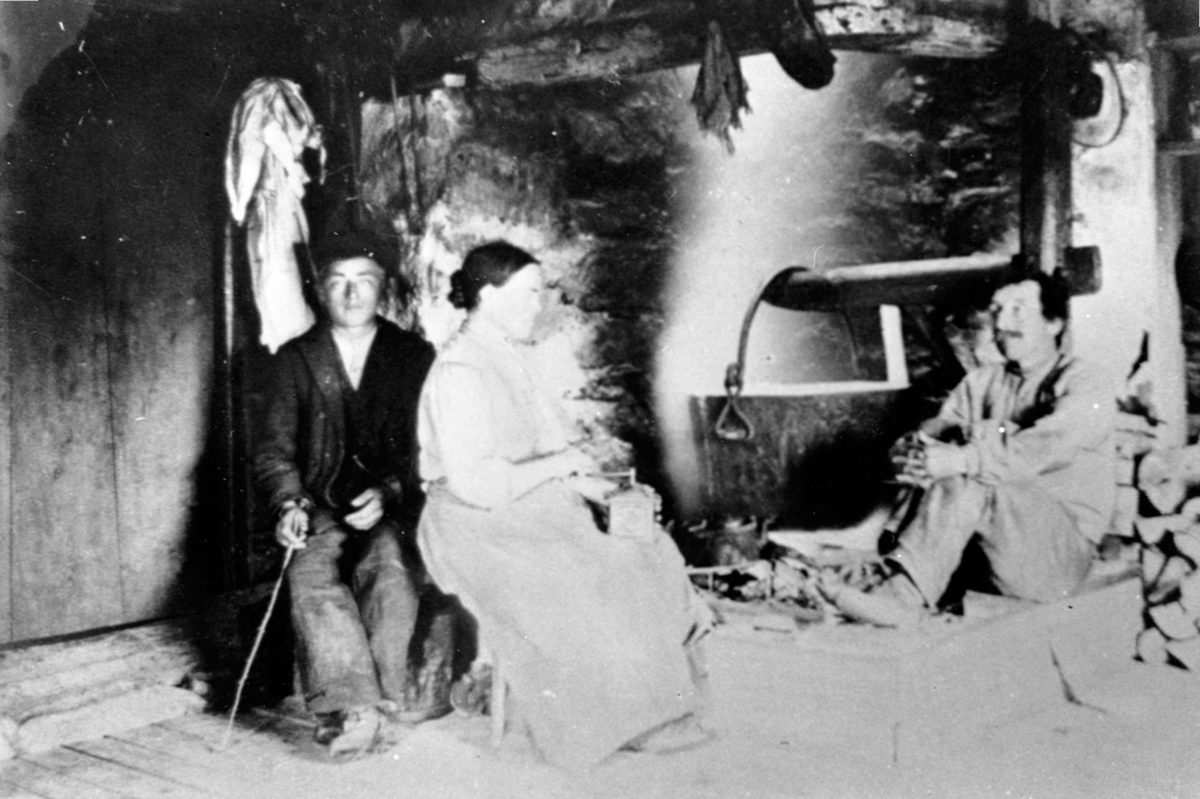 Anno Domkirkeodden, Interiør, seterhus for Bårdseth nedre på Gammelskolla, peis med jerngryte. Martin Bjørklund, Berte Bjørklund med kaffekvern, Peder Mikkelsen Bjørklund.
