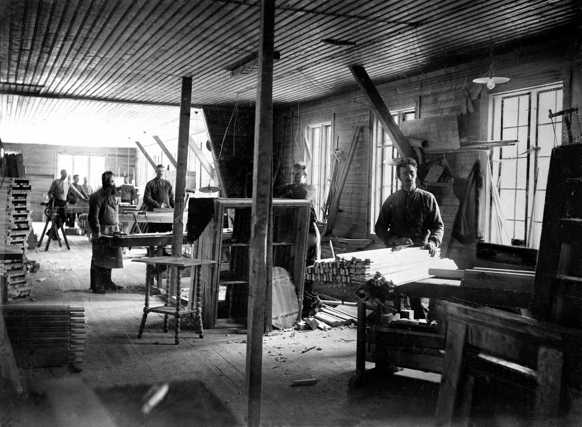 Anno Domkirkeodden, Interiør, maskin-snekkerverksted, 9 mann arbeider ved sag og pussemaskiner, aksler og drivreimer, Moelven Brug. Johan P. Næss med skjegg til venstre.