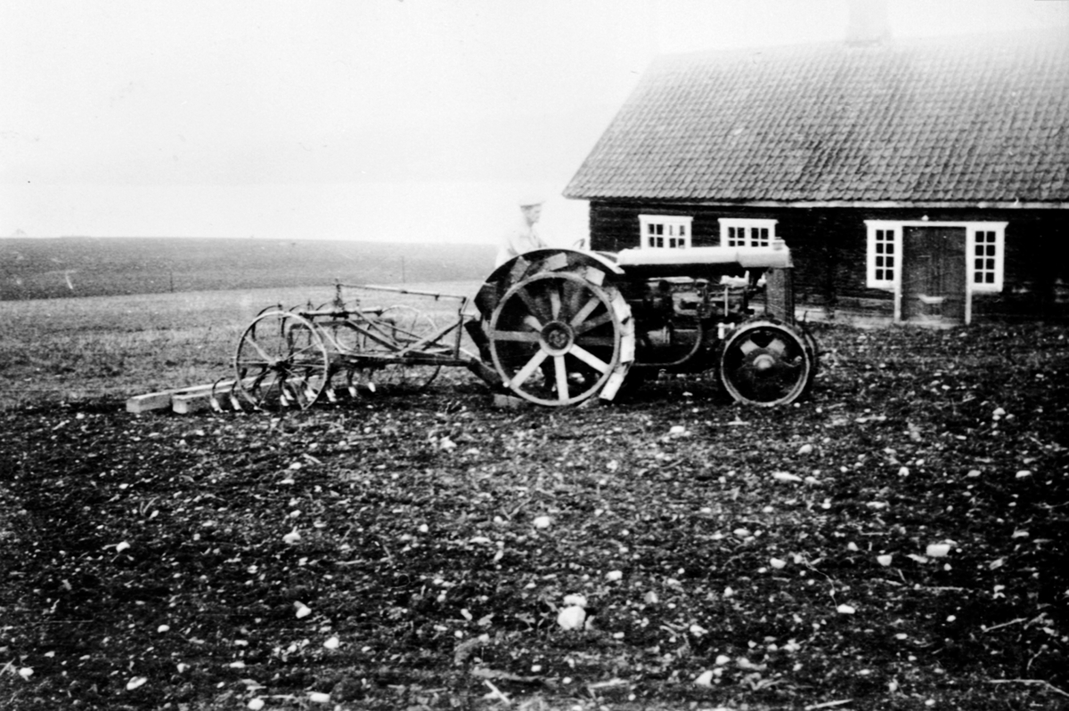 Anno Domkirkeodden, Våronn på Øvre Sund, Helgøya. Otto Sund (1884-1963) med jerntraktor av merke Fordson og exellent kultivatorharv på jordet ved Østre Sund. Hovedbygningen på Østre Sund i bakgrunn.